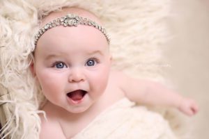 smiling 5-month-old baby girl wearing diamante headband